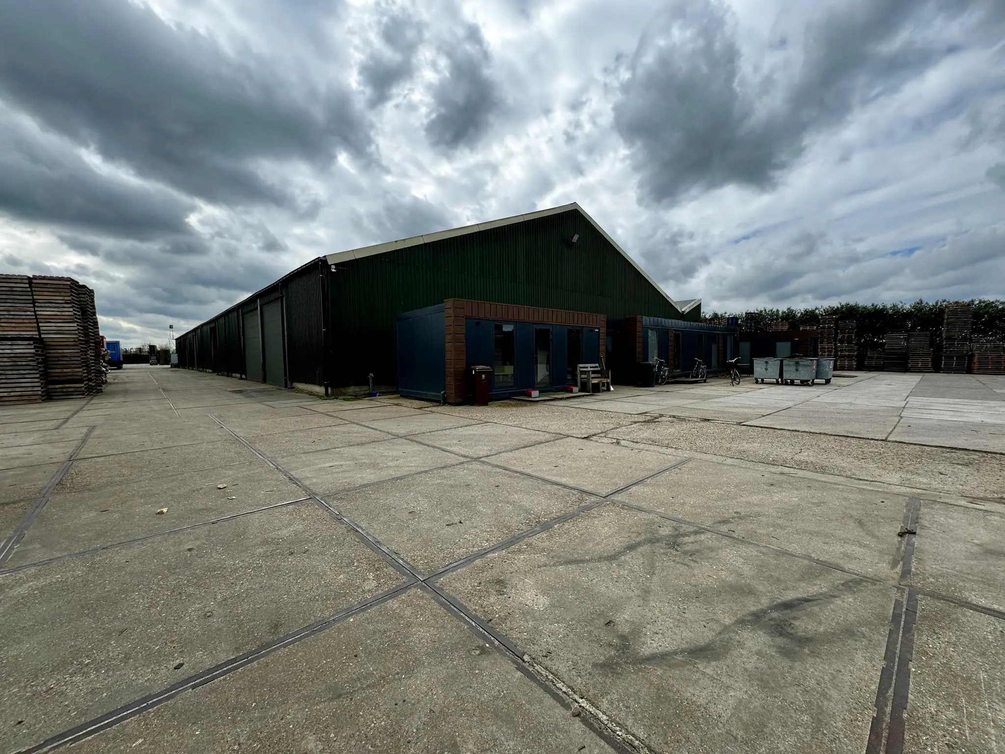 Industrieterrein met grote groene loods aan de Graaf van Lynden van Sandenburgweg onder een bewolkte lucht.